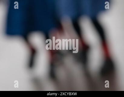 Drei Schulmädchen, die zur Schule gehen, tragen blaue Röcke und rote Socken. Absichtlich unscharfes Foto, um Schülerinnen abstrakt zu illustrieren Stockfoto