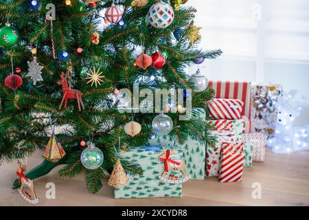 Ein wunderschön dekorierter Weihnachtsbaum mit verschiedenen Ornamenten und eingewickelten Geschenken darunter. Ein gemütliches Indoor Setting perfekt für die Weihnachtszeit, Meisterleistung Stockfoto