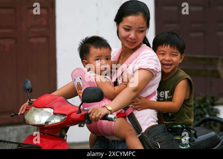 Laos, Luang Prabang. Mutter mit zwei Kindern auf dem Roller. Stockfoto