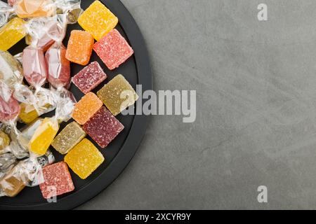 Verschiedene Gelee-Bonbons auf schwarzem Tablett, Draufsicht. Stockfoto