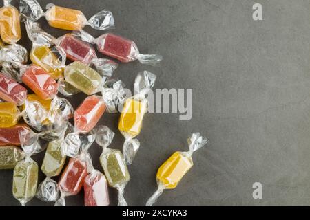 Verschiedene eingewickelte Gelee-Bonbons auf grauem Tisch, Draufsicht. Stockfoto