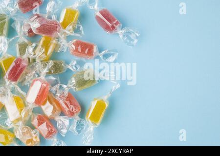 Verschiedene eingewickelte Gelee-Bonbons auf blauem Hintergrund, Draufsicht. Stockfoto