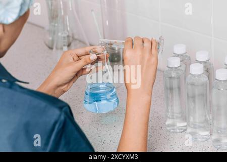 Frauen im Labor untersuchen die Wasserqualität mit einer mit Glasröhrchen gefüllten blauen chemischen Flüssigkeit für Forschung und Analyse im Labor Stockfoto