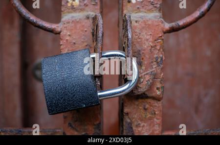 Nahaufnahme Eines Vorhängeschlosses, das ein altes Rusty Gate sichert, Internetsicherheitskonzept mit eingeschränktem Zugang, kein Zugangsgeheimnis Stockfoto