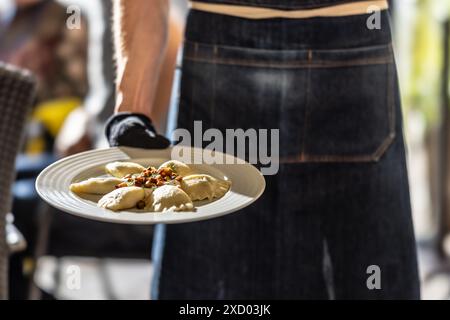 Der Kellner hält einen Teller mit traditionellen slowakischen Pirogi - Pirohi. Polnische Pierogi. Ukrainischer Verenyky. Stockfoto