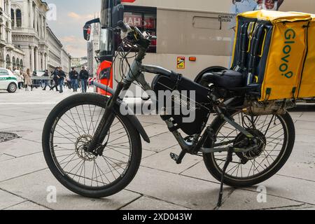 Ein Fahrrad der Glovo-Heimlieferung und ein Tourbus parken auf der Piazza del Duomo, dem Hauptplatz von Mailand, Lombardei, Italien Stockfoto