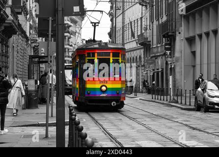 Schwarzweiß mit selektiver Farbe. Straßenbahn der Linie 10 mit Regenbogenflagge oder Stolz-Flagge, Symbol für LGBTQIA+ im Stadtzentrum von Mailand, Italien Stockfoto