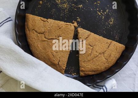 Tischfotografie der traditionellen estnischen Gerste Scone (Odrakarask), die in schwarzer Keramik gebacken werden, mit einem weißen Küchentuch Stockfoto