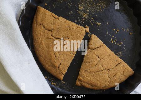 Tischfotografie der traditionellen estnischen Gerste Scone (Odrakarask), die in schwarzer Keramik gebacken werden, mit einem weißen Küchentuch Stockfoto