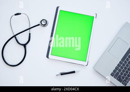Tablet, Green Screen und Stethoskop auf dem Schreibtisch im Krankenhaus für Wellness, App oder ui mit Mock-up-Platz. Digitaler Touchscreen, Laptop und medizinische Werkzeuge für Stockfoto