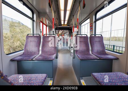 Innenraum der leeren niederländischen Straßenbahn, leere Sitze, weiße Wände, große Fenster Stockfoto