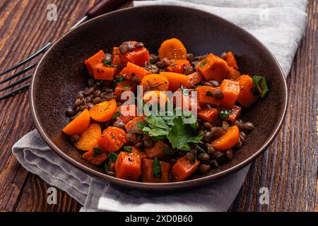 Komfortables Essen mit gebratenen Süßkartoffeln, Linsen, goldenen Berris und Kräutern, köstliches Mittag- oder Abendessen auf rustikalem Holztisch, Nahaufnahme Stockfoto