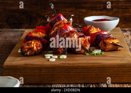 Hähnchenspieße mit roter Paprika und roten Zwiebeln auf Holzbrett Stockfoto