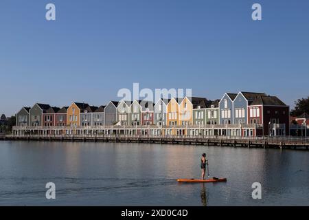 Paddeln Sie auf einem Surfbrett auf dem Rietplas See vorbei an den bunten Regenbogenhäusern im Dorf Houten in der Provinz Utrecht. Stockfoto