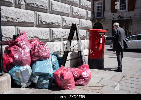 Ein Mann postet am 19. Juni 2024 einen Brief in das Postfach auf Bell Yard in der City of London, dem Finanzviertel der Hauptstadt. Stockfoto