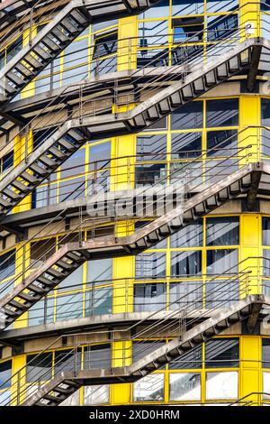 Ein antikes Industriegebäude mit markanten Nottreppen und großen gelben Fenstern, das sein historisches architektonisches Design zeigt. Stockfoto