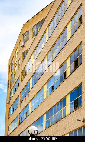 Ein antikes Industriegebäude mit einer großen Fassade mit gelben Fenstern, die sein historisches architektonisches Design zeigen. Stockfoto