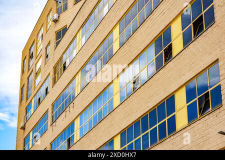 Ein antikes Industriegebäude mit einer großen Fassade mit gelben Fenstern, die sein historisches architektonisches Design zeigen. Stockfoto