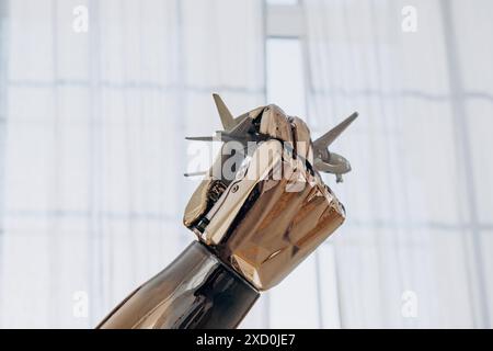 Eine Nahaufnahme eines robotergestützten bionischen Arms mit Metallspitzen simuliert den Flug eines Flugzeugs vor dem Hintergrund eines Fensters im Viertel, das Konzept eines Reiseträums. Roboterhand mit Stacheln Stockfoto