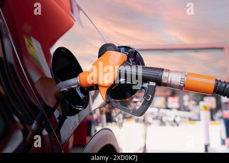 Ein Auto wird an einer Tankstelle mit Benzin gefüllt. Die Gaspumpe ist orange und schwarz Stockfoto