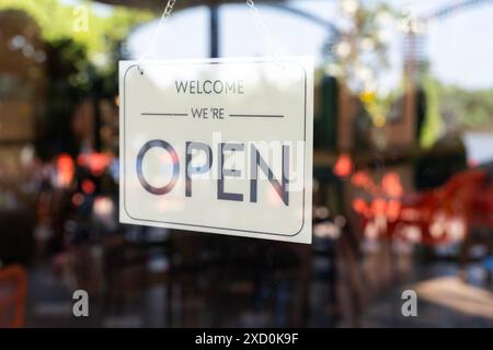 Ein Schild an einem Fenster mit der Aufschrift „Willkommen, wir sind offen“ Stockfoto