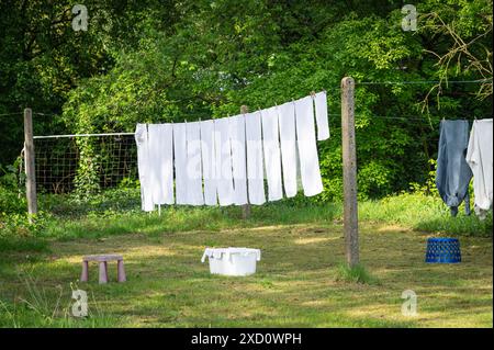 Weiße Wäsche auf Wäscheleinen im Garten. Weiße Handtücher trocknen in der Sonne. Stockfoto