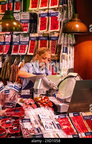 Frau, die Fleisch auf dem Markt La Boqueria schneidet - Mercat Boqueria Barcelona, Katalonien, Spanien. Stockfoto