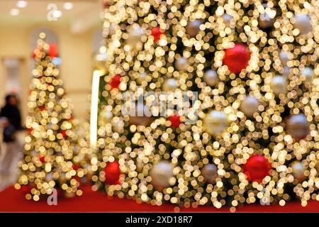 Verschwommener Blick auf opulent beleuchtete Weihnachtsbaumdekorationen im Einkaufszentrum während der Weihnachtszeit Stockfoto