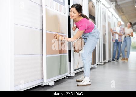 Die junge Frau wählt Kacheln im Eisenwarenladen Stockfoto