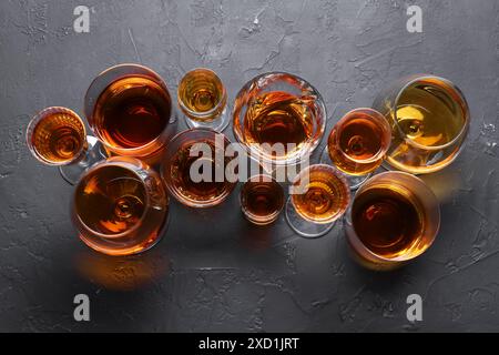 Viele verschiedene Liköre in Gläsern auf dunkel strukturiertem Tisch, flach gelegt Stockfoto