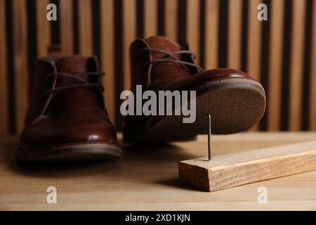 Metallnagel in Holzplanke und Schuhe auf dem Tisch Stockfoto