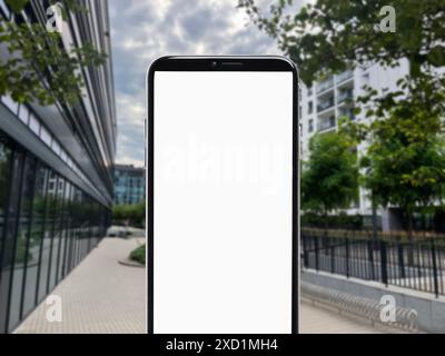 Mobiltelefon mit leerem Bildschirm gegenüber der Stadtstraße. Platz für Design Stockfoto