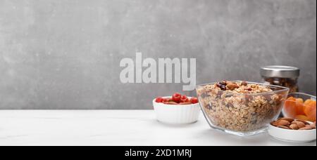 Hausgemachtes Müsli mit Nüssen und getrockneten Früchten auf weißem Tisch. Bannerdesign mit Platz für Text Stockfoto