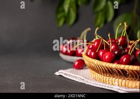 Nahaufnahme eines Korbkörpers, gefüllt mit frischen, roten Kirschen, auf einem Tuch Stockfoto