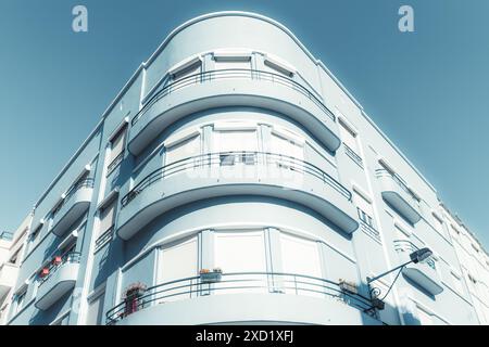 Ein modernes Wohngebäude mit geschwungenen Balkonen und blauen Außenwänden. Das Gebäude hat mehrere Etagen, jedes mit Fenstern mit Fensterläden und Stockfoto