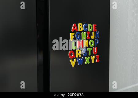 Alphabetische Reihenfolge. Viele helle magnetische Buchstaben auf dem Kühlschrank in Innenräumen Stockfoto