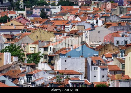 Blick aus der Vogelperspektive auf die weißen und pastellfarbenen alten Gebäude mit roten Ziegeldächern in der charmanten, gewundenen Altstadt von lissabon Stockfoto