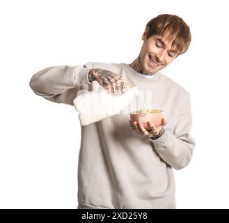 Mann, der Milch in eine Schüssel mit Müsliringen auf weißem Hintergrund gießt Stockfoto