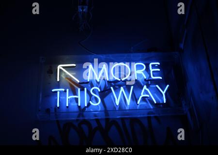 Ein leuchtend blaues Neonschild „More This Way“ Stockfoto