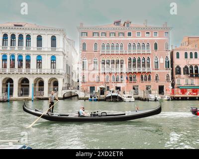 Venedig, Italien - 20. Juni 2021 Gondoliere gleitet durch den Kanal, während Sie die Gondel steuern, während Touristen die Sehenswürdigkeiten in venedig, italien, besichtigen Stockfoto