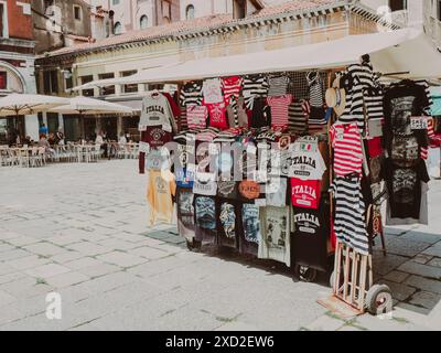 Venedig, Italien - der Souvenirkiosk am 20. Juni 2021 zeigt farbenfrohe T-Shirts und andere Kleidungsstücke zum Verkauf auf einer sonnigen italienischen piazza Stockfoto