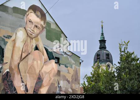 Straßenbild mit dem Titel „Evropski Amazon“ auf dem Hintergrund der Glockenturm Kirche St. Georg in Sombor, Vojvodina, Serbien; erstellt für den Tag des Amazonas von Europa in Stockfoto