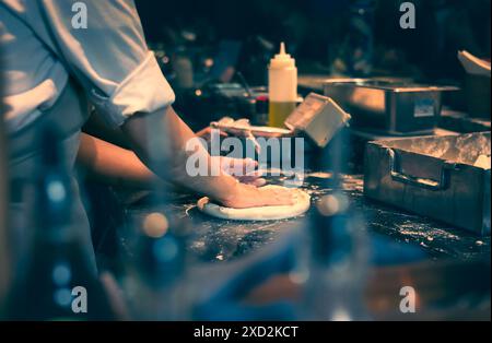 Die Hände kneten den Teig für die Pizzazubereitung. Der Pizzakoch macht den Pizzateig im Restaurant. Roher Pizzateig. Nahaufnahme des Küchenchefs, der Pizza zubereitete. Stockfoto