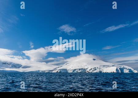 Eine beschauliche antarktische Landschaft in der Nähe des Hafens Mikkelsen auf Trinity Island, mit starken Reflexen, zerklüfteten Bergen und beeindruckenden Eisbergen Stockfoto