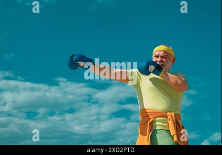 Schöner älterer Mann, der Boxkick übt. Älterer sportlicher Mann im Boxsport, der Übungen mit Boxhandschuhen macht. Ich liebe Boxen. Stockfoto