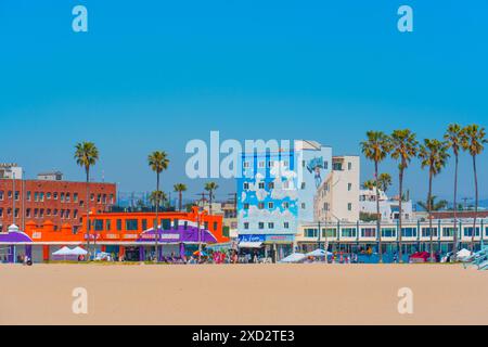 Los Angeles, Kalifornien - 3. April 2024: Blick vom Venice Beach aus mit farbenfrohen Gebäuden und Marktständen entlang der Strandlinie vor einem klaren B Stockfoto