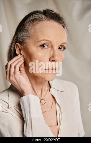 Die reife Frau strahlt in einem weißen Hemd Gnade aus, die in eine Pose schlägt. Stockfoto