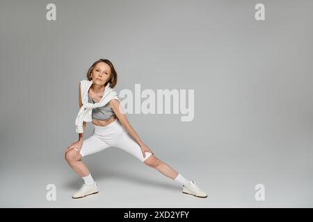 Eine junge Frau posiert anmutig vor einem weichen grauen Hintergrund. Stockfoto