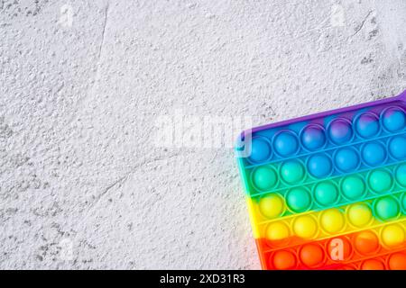 Draufsicht auf Regenbogen-Antistress sensorisches Spielzeug zappeln Push Pop it auf Stein Hintergrund Stockfoto