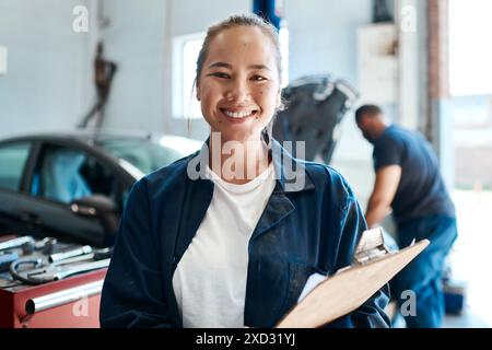 Frau, Mechaniker und Klemmbrett für Reparaturarbeiten, Fahrzeugwartung und Sicherheitsprüfung im Werkstattporträt. Gesicht eines asiatischen Ingenieurs oder Arbeiters mit Stockfoto